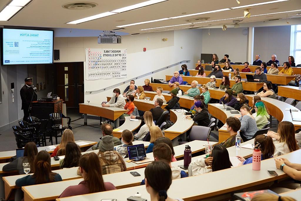 学生们在演讲厅里听一位气候讲座的演讲者讲话